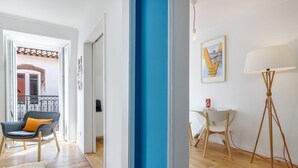 Un salon moderne avec un mur d’accent bleu, un fauteuil gris agrémenté d’un coussin moutarde, un lampadaire blanc et une petite table avec une chaise.