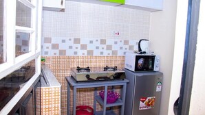 Een compacte keuken met een gasfornuis, een magnetron en een kleine koelkast.