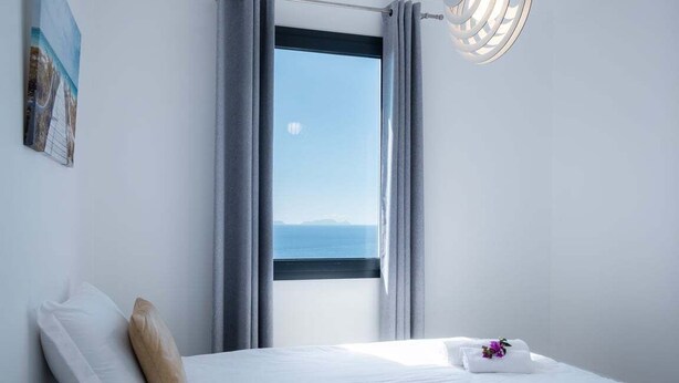 A hotel room with a bed, a window with curtains, a wall-mounted light fixture, and a small painting. - GuestReady - Leme Beach Breathtaking Views (Santa Cruz)