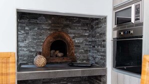 A kitchen with a stone fireplace, a microwave, and an oven. - GuestReady - Leme Beach Breathtaking Views (Santa Cruz)