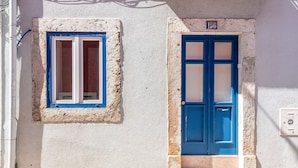 A building with a blue door and window, a number '196' above the door, and a utility box on the wall. - GuestReady - Pink Sunset (Lisbon)