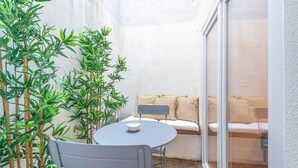 A small patio with a round table, two chairs, a sofa with cushions, and bamboo plants. - GuestReady - Pink Sunset (Lisbon)