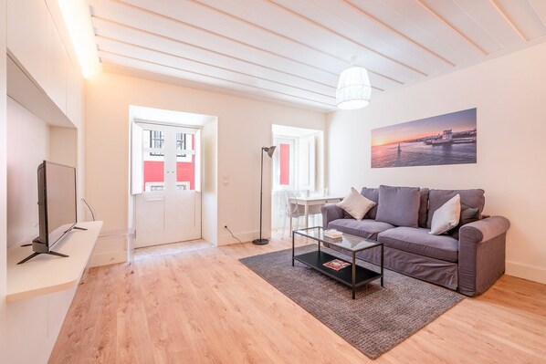 Una sala de estar moderna con sofá, mesa de centro y televisor sobre un mueble.