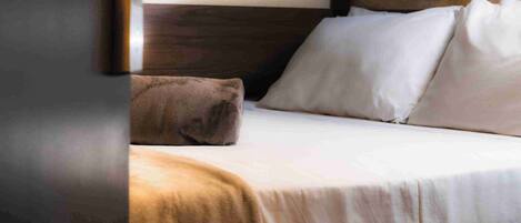 A hotel room with a bed, a wooden headboard, and a door.