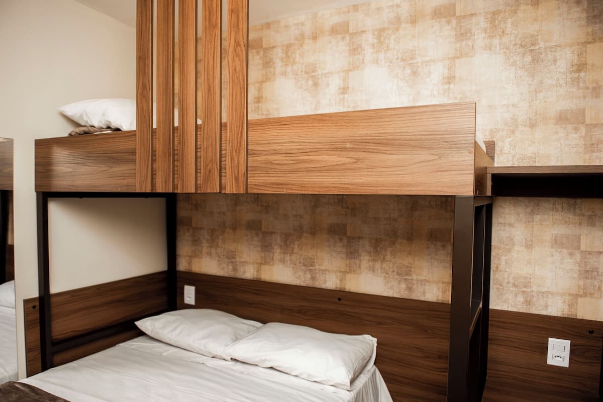 A bunk bed room with wooden headboards and a textured wall.