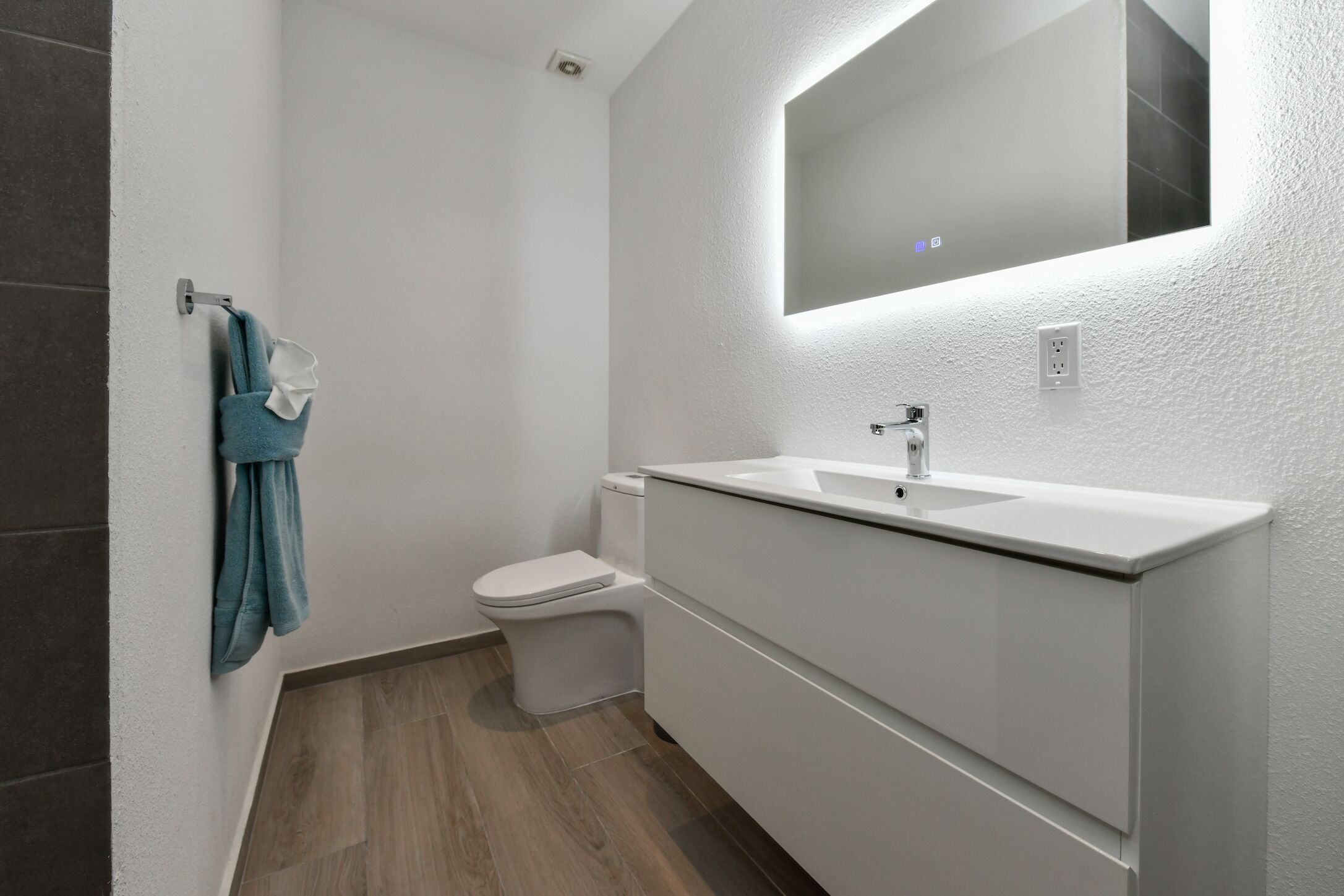 A modern bathroom with a white sink, a mirror, and a toilet.