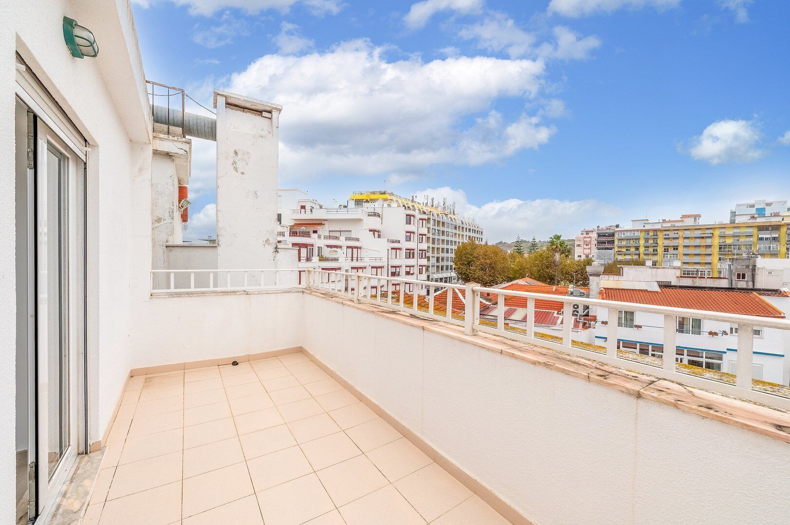 A balcony with a tiled floor and a white railing.