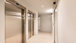 A corridor with three elevators and a door at the end.