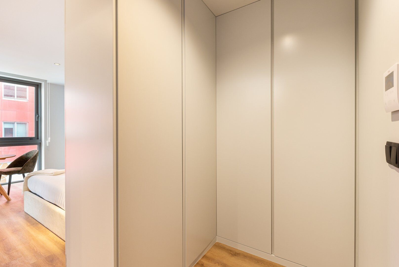 Une chambre moderne avec une grande armoire, un lit et une petite table avec une chaise.