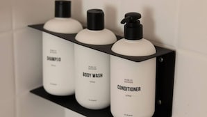 Three white bottles of shampoo, body wash, and conditioner on a black shelf. - Peaceful 1BR Apt 10-Mins to Nashville (Nashville)