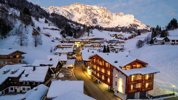 A snow-covered village with wooden buildings and a mountain backdrop.