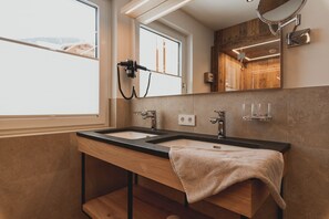 A modern bathroom with two sinks, a towel, a mirror, and a window. - Portis Appartements (Dienten am Hochkoenig)
