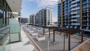 Une terrasse sur le toit, avec des immeubles modernes en arrière-plan, des sièges en plein air et un ciel dégagé.