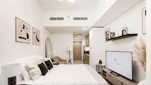 Une chambre à coucher moderne, avec un lit, une télévision et des œuvres d’art accrochées aux murs.