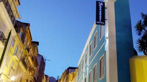 A narrow street lined with multi-story buildings, one with a sign reading "SAUDADE Apartments". - Saudade Micro Lofts (Lisbon)