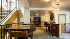 A spacious dining area with a wooden table and chairs, a staircase with metal railings, and a bookshelf in the background. - Phoenix 207 2 Bedroom Condo by RedAwning (Steamboat Springs)