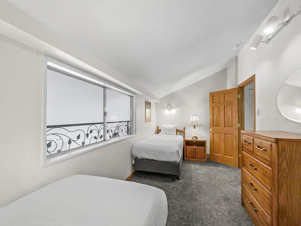 A bedroom with a large window, two beds, a dresser, and a nightstand. - Cj404 Copper Junction 3 Bedroom Condo by RedAwning (Copper Mountain)