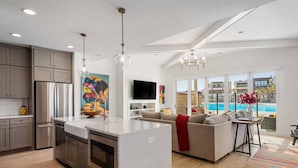 A modern kitchen with a central island, stainless steel appliances, and a large window overlooking a pool.