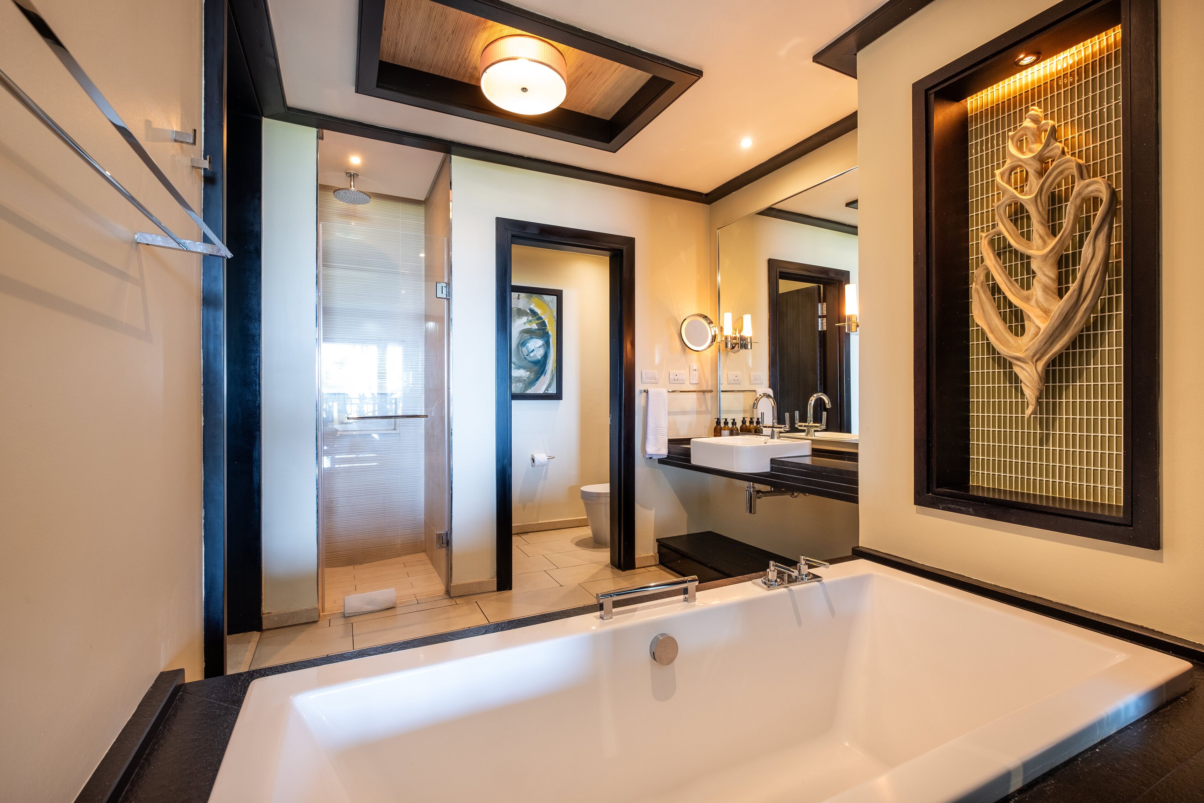 Un baño moderno con una bañera grande, una ducha a ras de suelo y un tocador con espejo y lavabo.