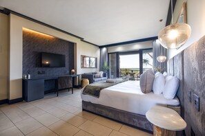 Una camera d'hotel moderna con un ampio letto, TV, scrivania e balcone con vista.