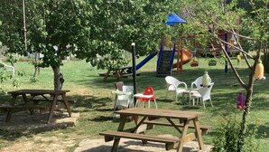 A playground with a slide, swings, and picnic tables. - family motel bungalov (Kesan)