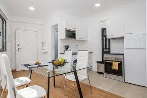 Una cocina moderna con armarios blancos, una mesa de comedor de vidrio y un horno empotrado.