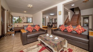 A spacious living area with two sofas, a coffee table, and a staircase leading to an upper floor. - Xplore Indo - Onella (Kotagiri)