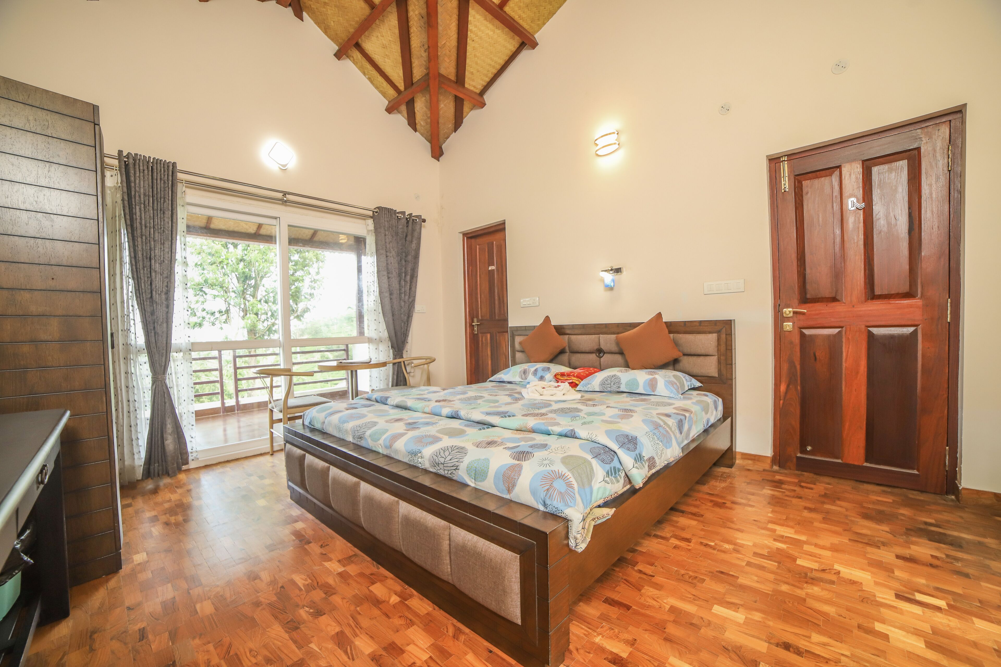 Un dormitorio con cama de madera, un escritorio, una ventana con cortinas y una puerta.