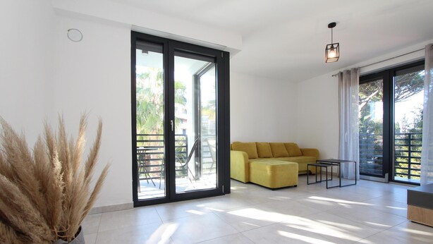 A modern living room with a yellow sofa, a coffee table, and a potted plant. - Apartments Katarina (Rovinj)