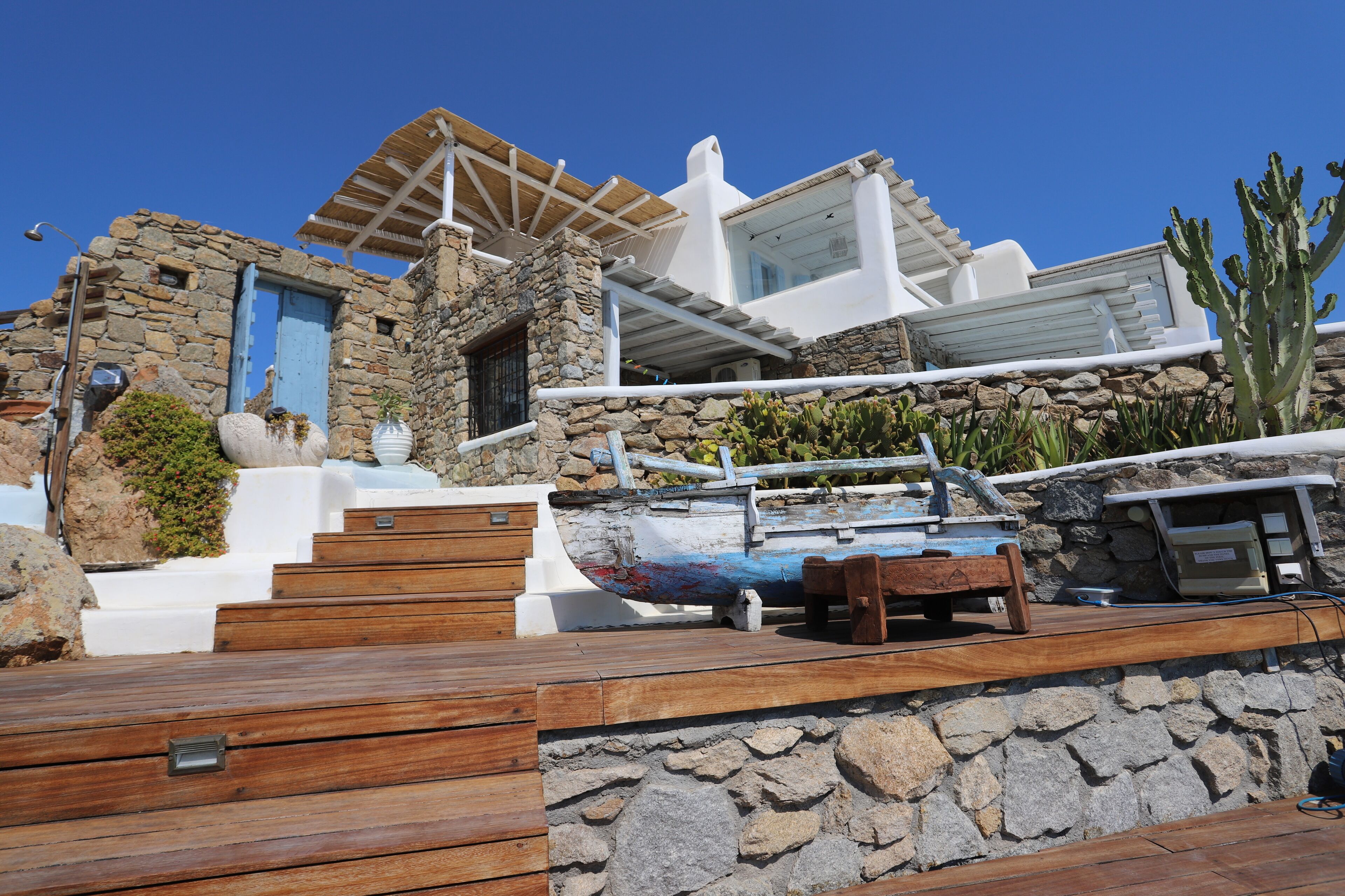 A stone building with a wooden deck, a boat, and a cactus.