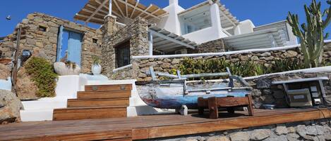 A stone building with a wooden deck, a boat, and a cactus.