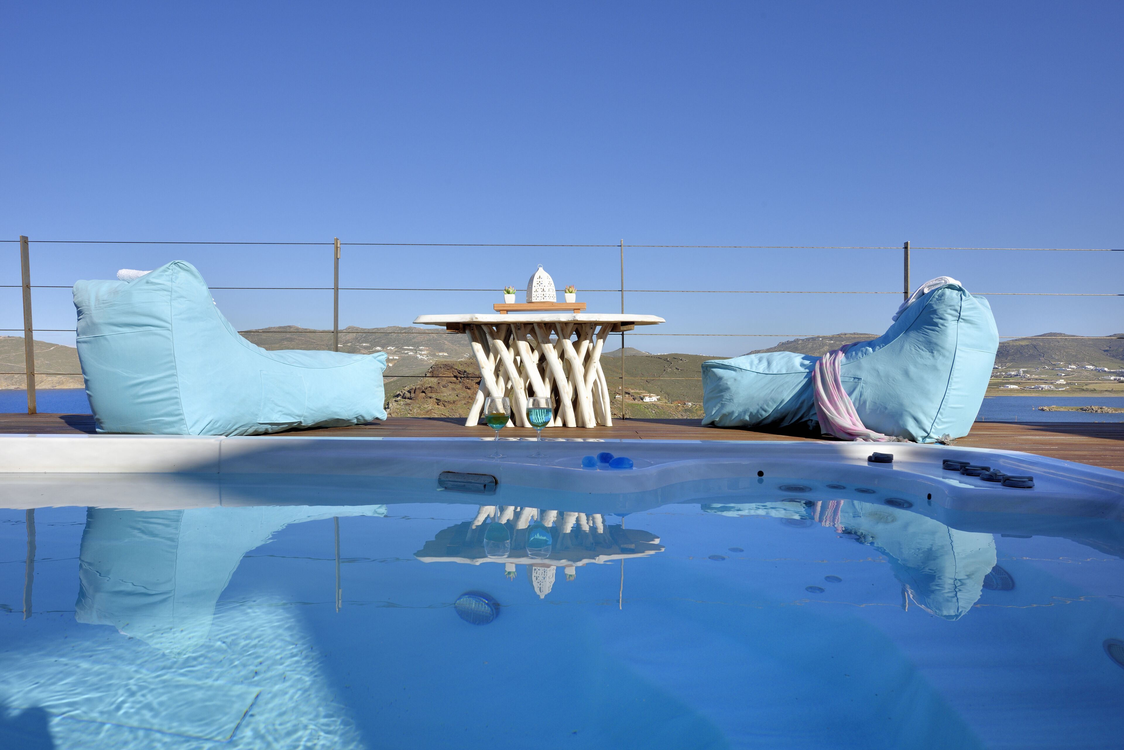Une piscine avec deux chaises bleues et une petite table agrémentée d’un objet décoratif.