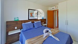 A neatly arranged hotel room with a bed, a bedside table, a nightstand, a wardrobe, and a framed picture on the wall. - Paraíso na Reserva Imbassaí (Mata de São João)