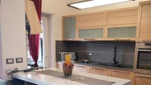 A modern kitchen with a central island, two bar stools, a built-in oven, and a pendant light. - J u b i l e h o u s e R o m e (Roma)