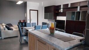 A modern kitchen with a marble countertop, wooden cabinets, and a dining area with a sofa and chairs. - J u b i l e h o u s e R o m e (Roma)