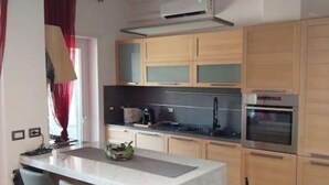 A modern kitchen with a central island, bar stools, wooden cabinets, a built-in oven, and a ceiling-mounted air conditioner. - J u b i l e h o u s e R o m e (Roma)
