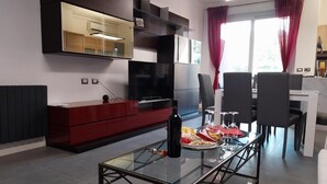 A modern living room with a glass coffee table, red and black furniture, a flat-screen TV, and a dining area with chairs and a table. - J u b i l e h o u s e R o m e (Roma)