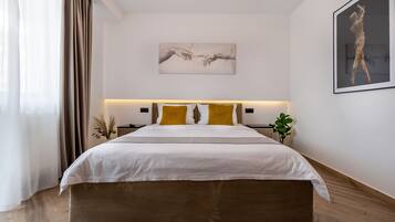 A modern bedroom with a large bed, two bedside tables, a wall-mounted artwork, and a potted plant.