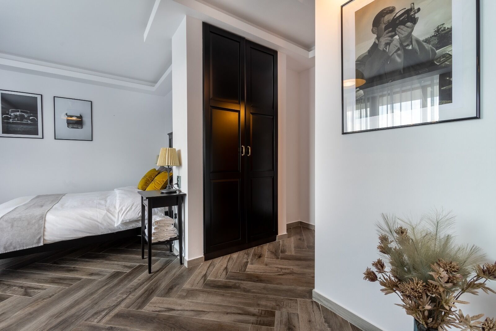 A bedroom with a bed, bedside table, lamp, and a wardrobe.