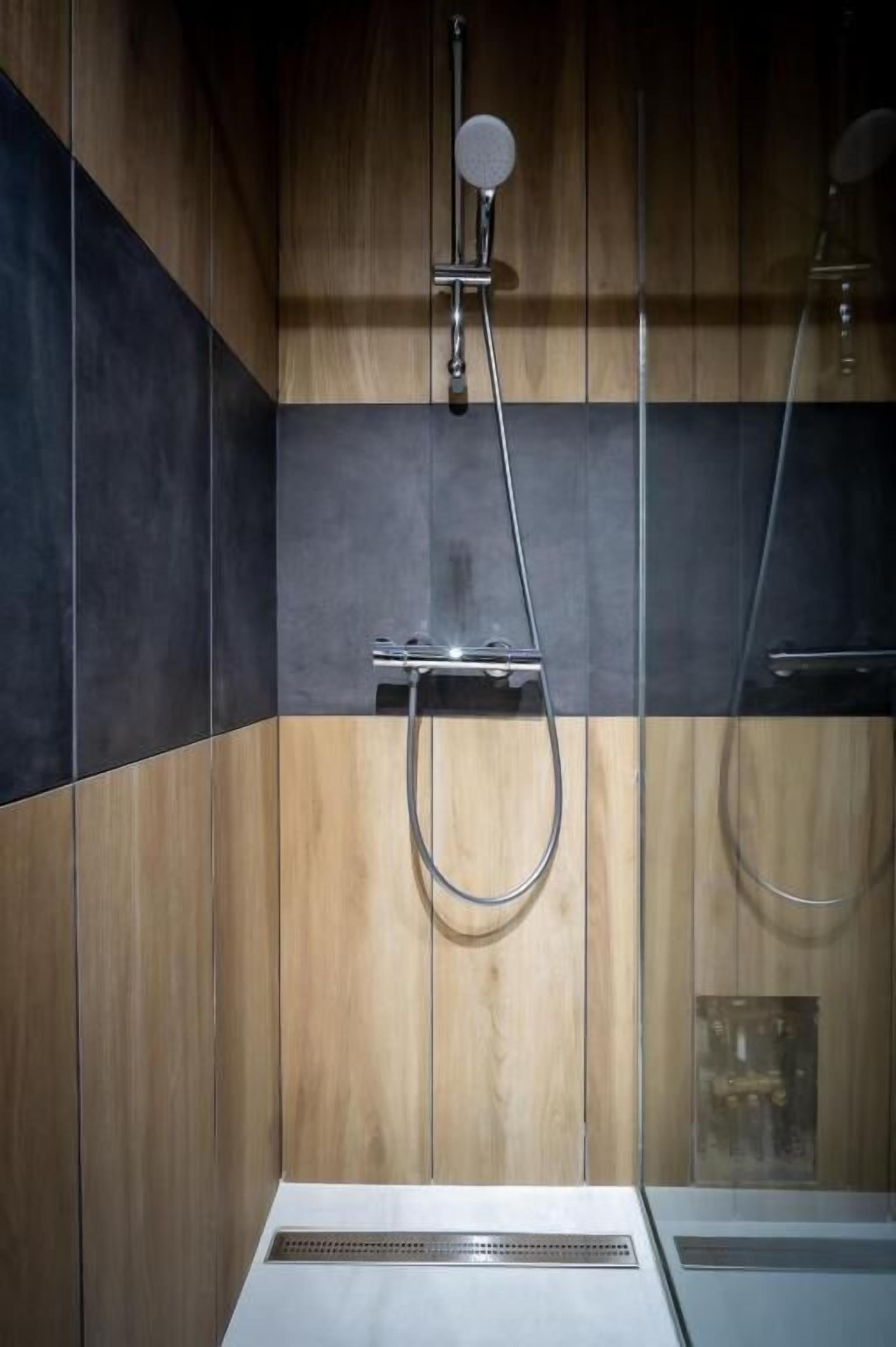 Un área de ducha moderna con cabezal de ducha de mano y grifo empotrado.