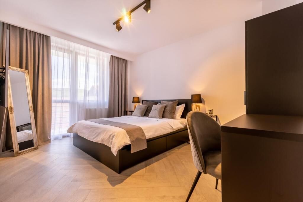 Una habitación de hotel moderna con una cama grande, un escritorio y una silla.
