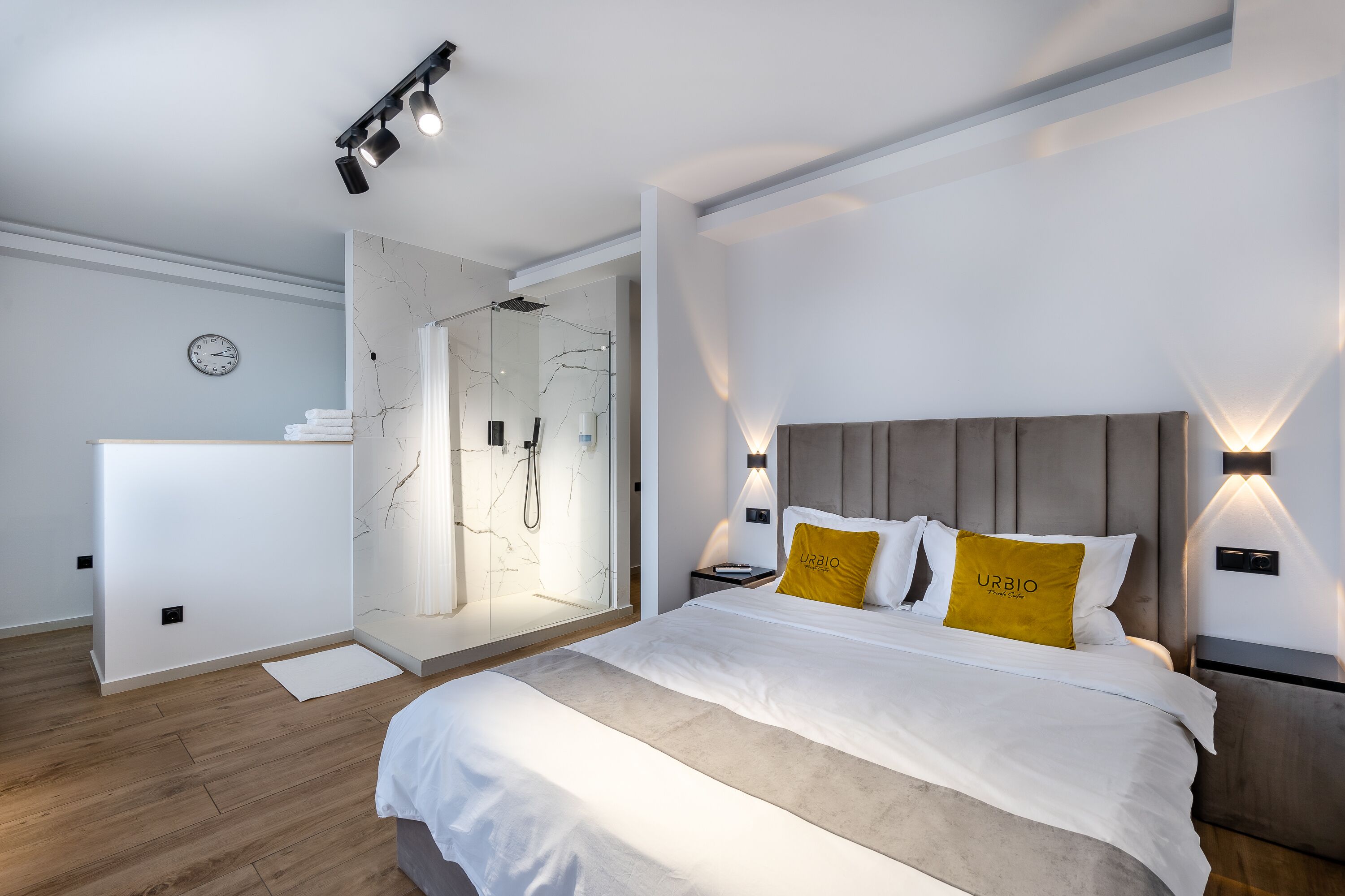 Un dormitorio moderno con una cama grande, ducha a ras de suelo y un diseño minimalista.