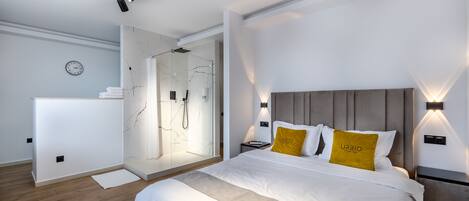 Un dormitorio moderno con una cama grande, ducha a ras de suelo y un diseño minimalista.