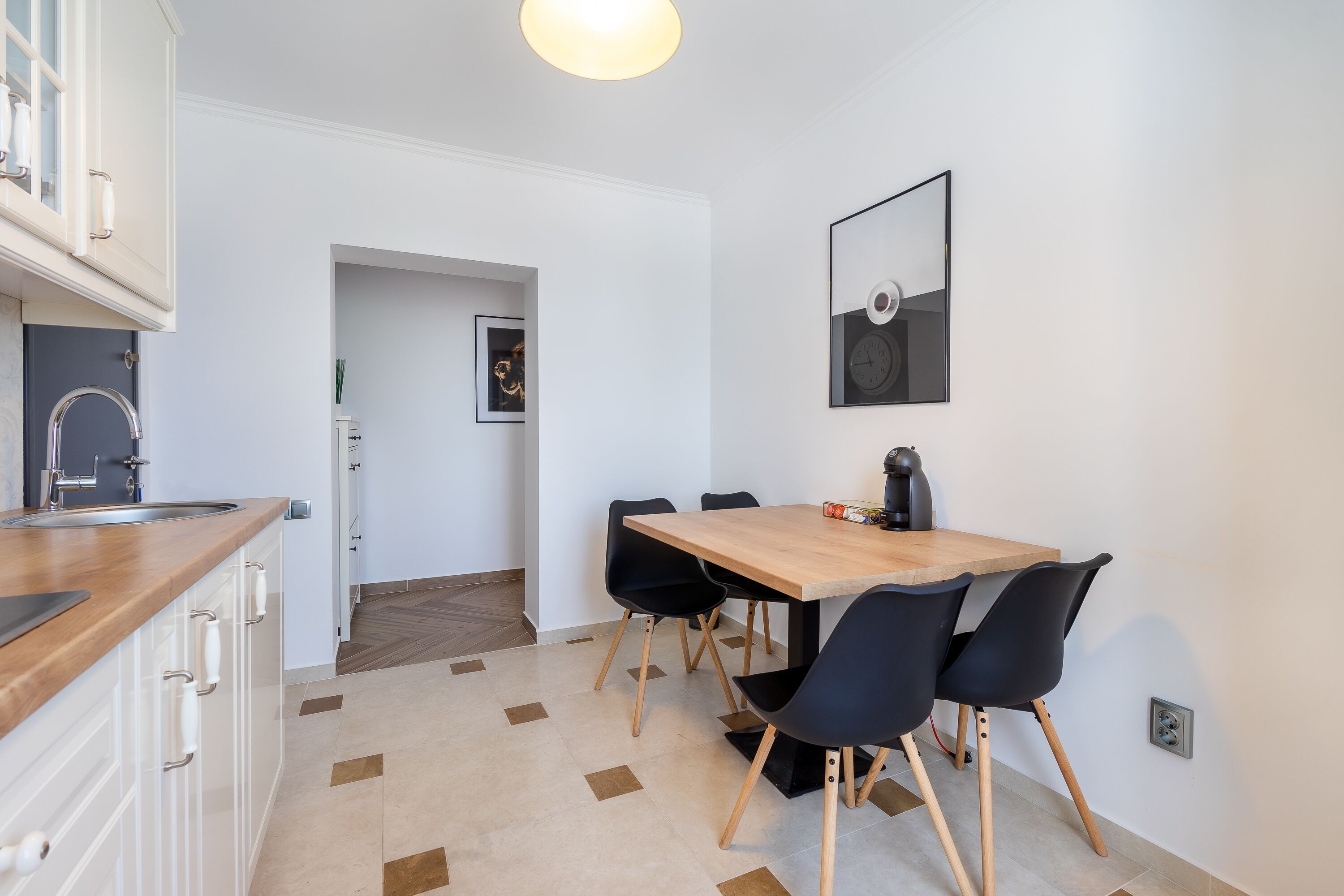 Eine moderne Küche mit Holzarbeitsplatte, weißen Schränken und einem Essbereich mit Holztisch und schwarzen Stühlen.