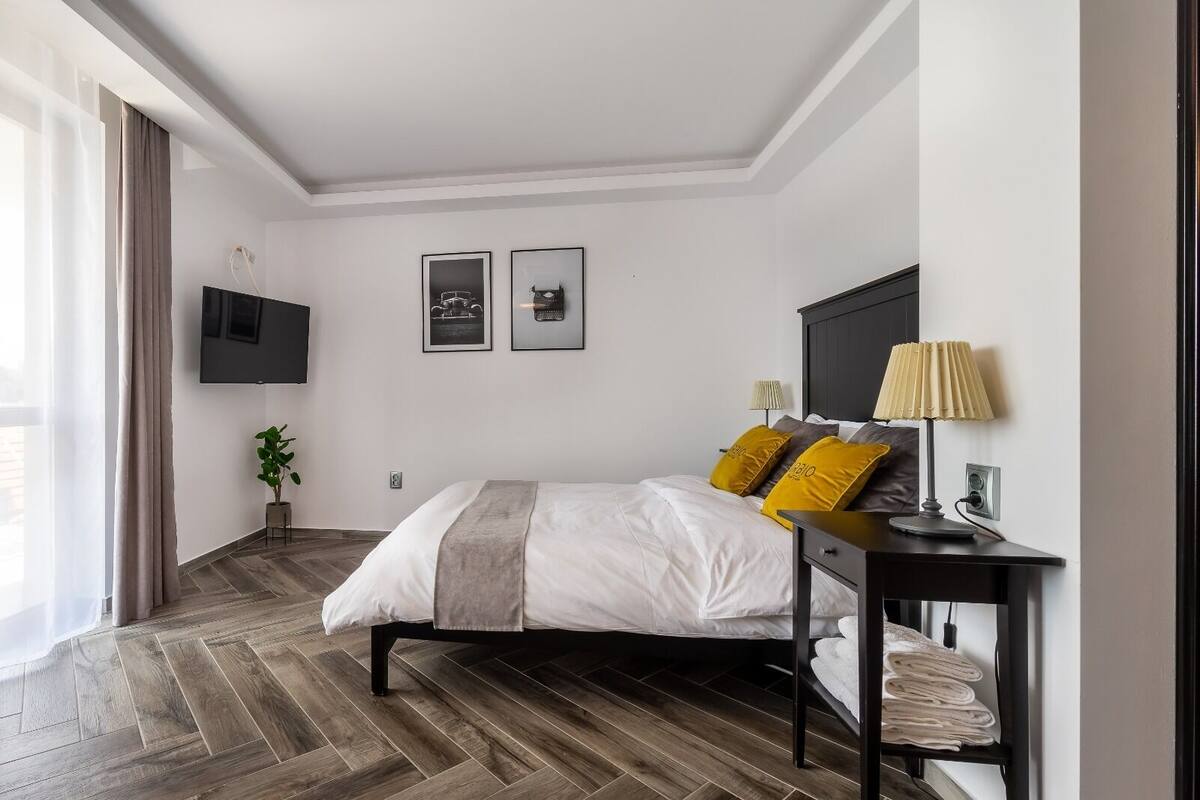 A modern bedroom with a bed, a bedside table, a lamp, a TV, and two framed pictures on the wall.