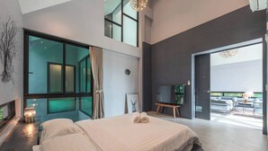 Une chambre moderne avec un grand lit, une télévision et une vue sur l’extérieur.