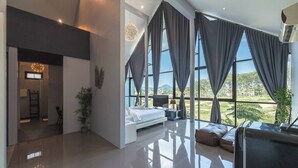 Une chambre moderne avec un grand lit, une télévision et une vue sur l’extérieur.