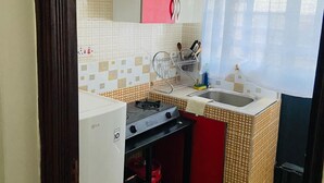 Eine kleine Küche mit Gaskochfeld, Spüle und kleinem Kühlschrank.