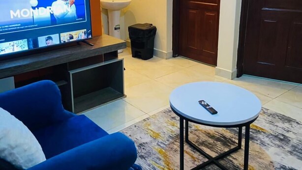 Ein Wohnzimmer mit Fernseher, Sofa und einem kleinen runden Tisch.