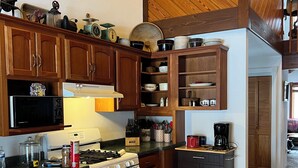 A kitchen with wooden cabinets, a stove, microwave, and various kitchen items. - Private 27 acres in peaceful Tapiola MI   Great home base to explore Western UP. (Chassell)